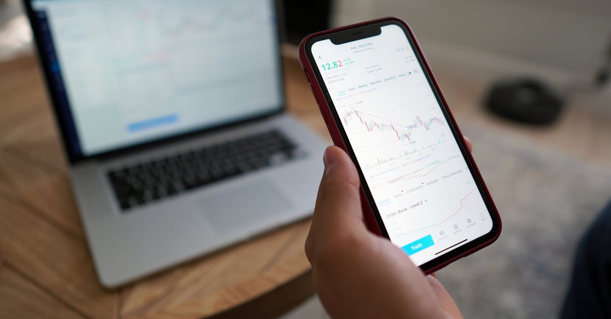 A person trading stocks on a smartphone and laptop. Ideal for finance themes.