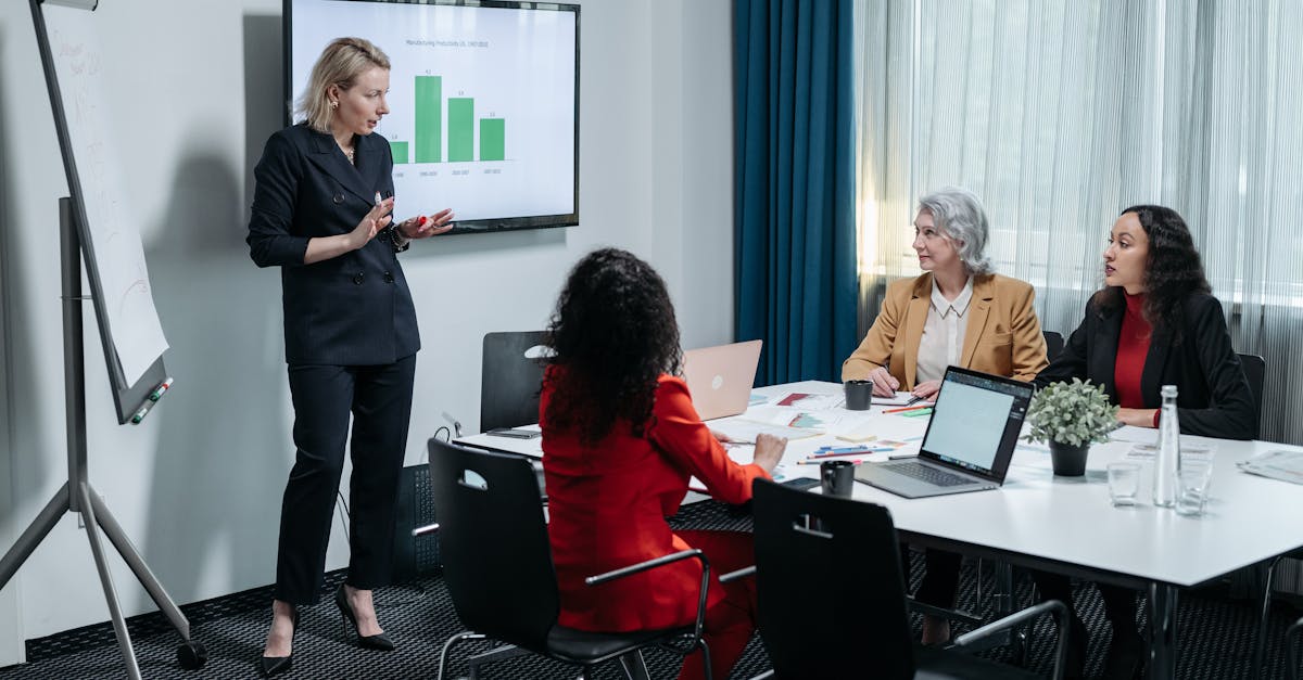 A group of professional women engaged in a business presentation in a modern conference room.