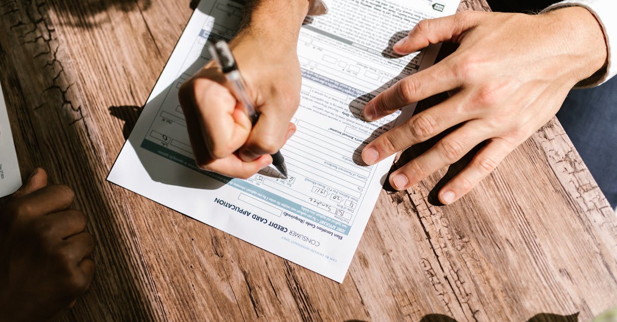 Hands writing on a consumer loan credit application form on a wooden table.