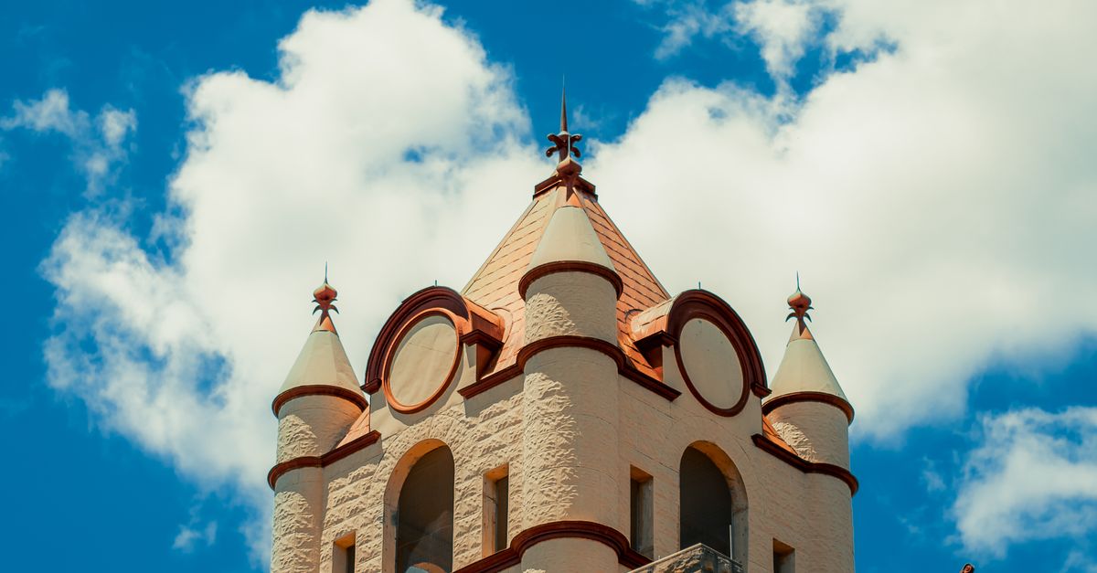 A stunning historic building in Brady, Texas with a vibrant red roof against a blue sky and white clouds.