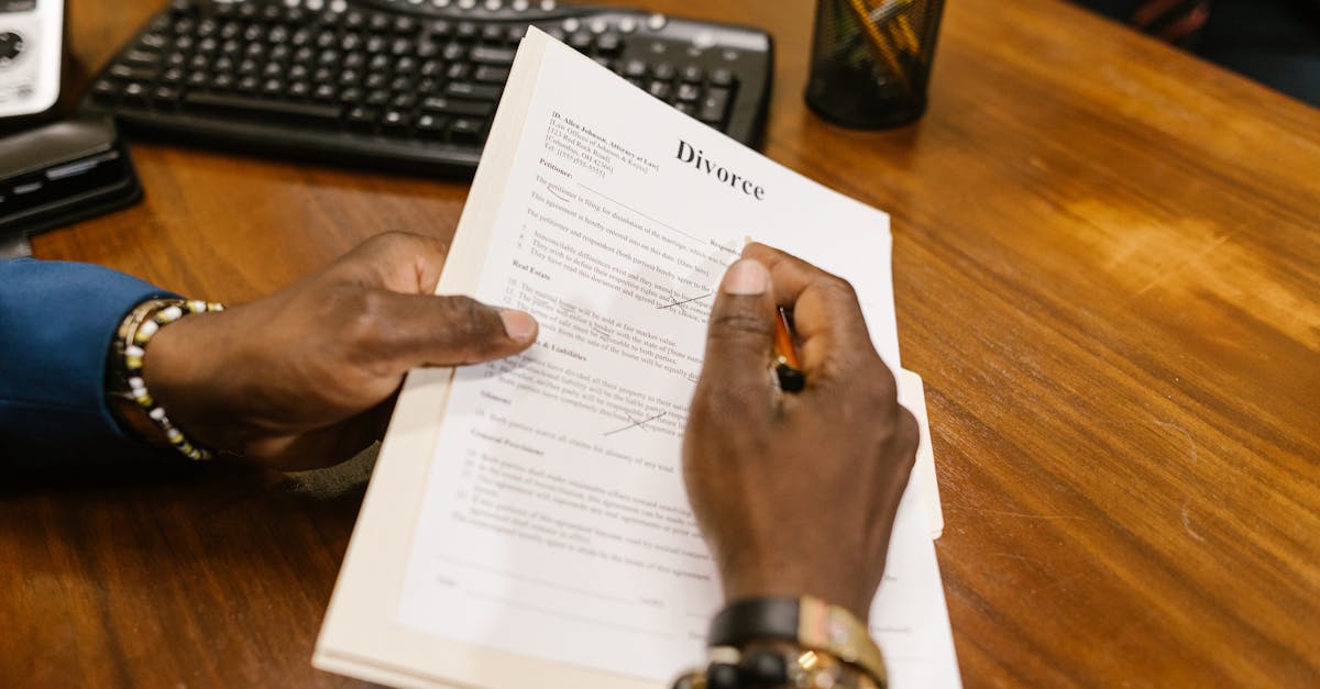 A person signs official divorce documents at an office desk.
