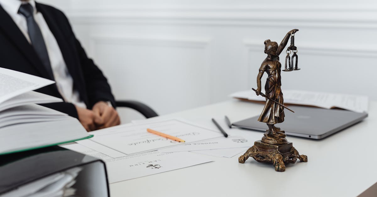 A legal professional's workspace featuring Lady Justice statue, documents, and a laptop.