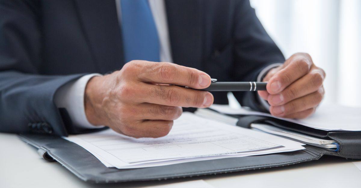Businessman in suit holding pen, ready to sign documents. Close-up detail shot.