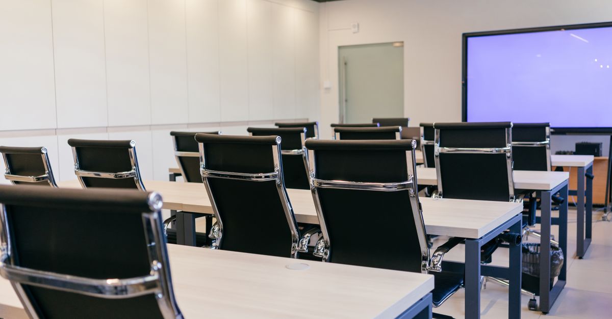 Spacious, modern conference room with black chairs and a projection screen.