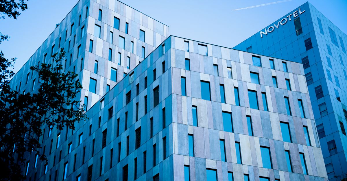 Blue-toned modern architecture of Novotel in Barcelona under a clear sky.