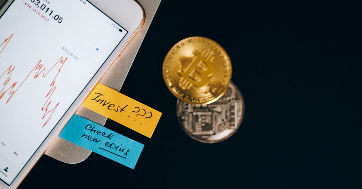 Bitcoin coins and smartphone displaying price chart with investment notes.