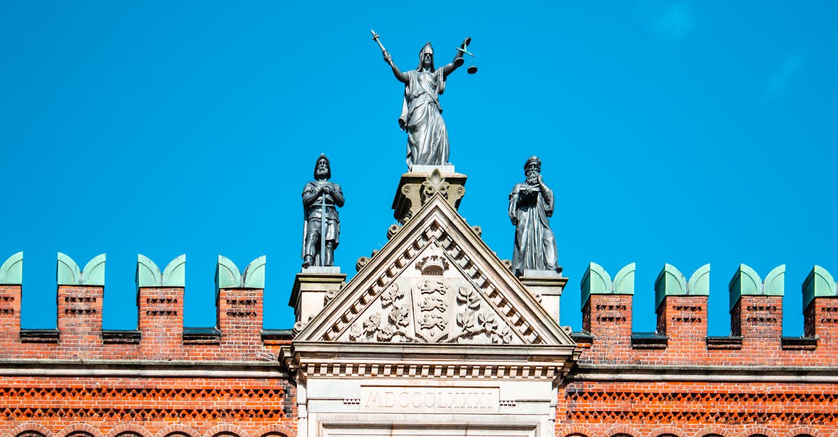 Stunning facade of Odense courthouse with Lady Justice statue under clear blue skies.