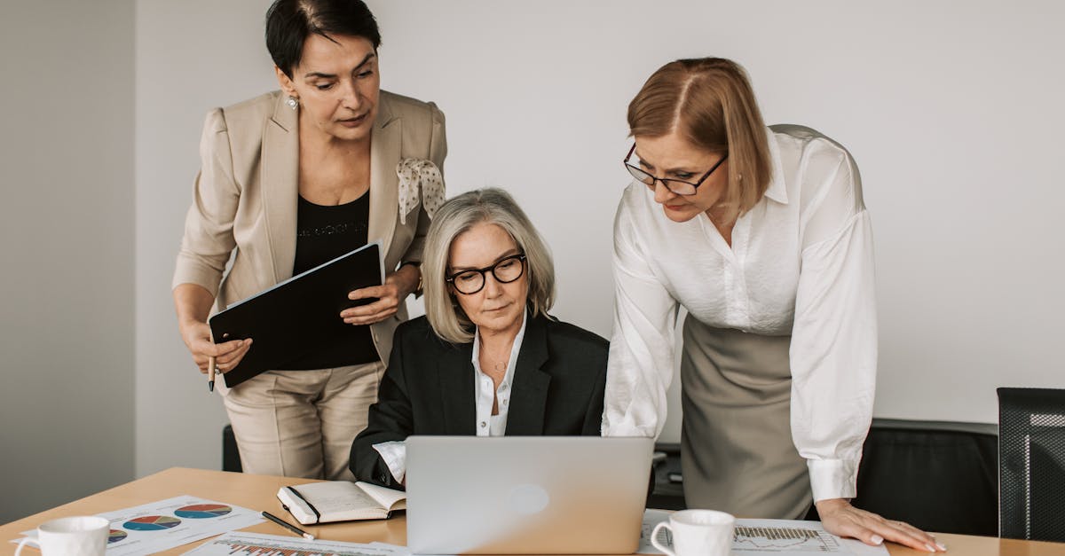 Three women in a business meeting, discussing strategy with charts and laptop.