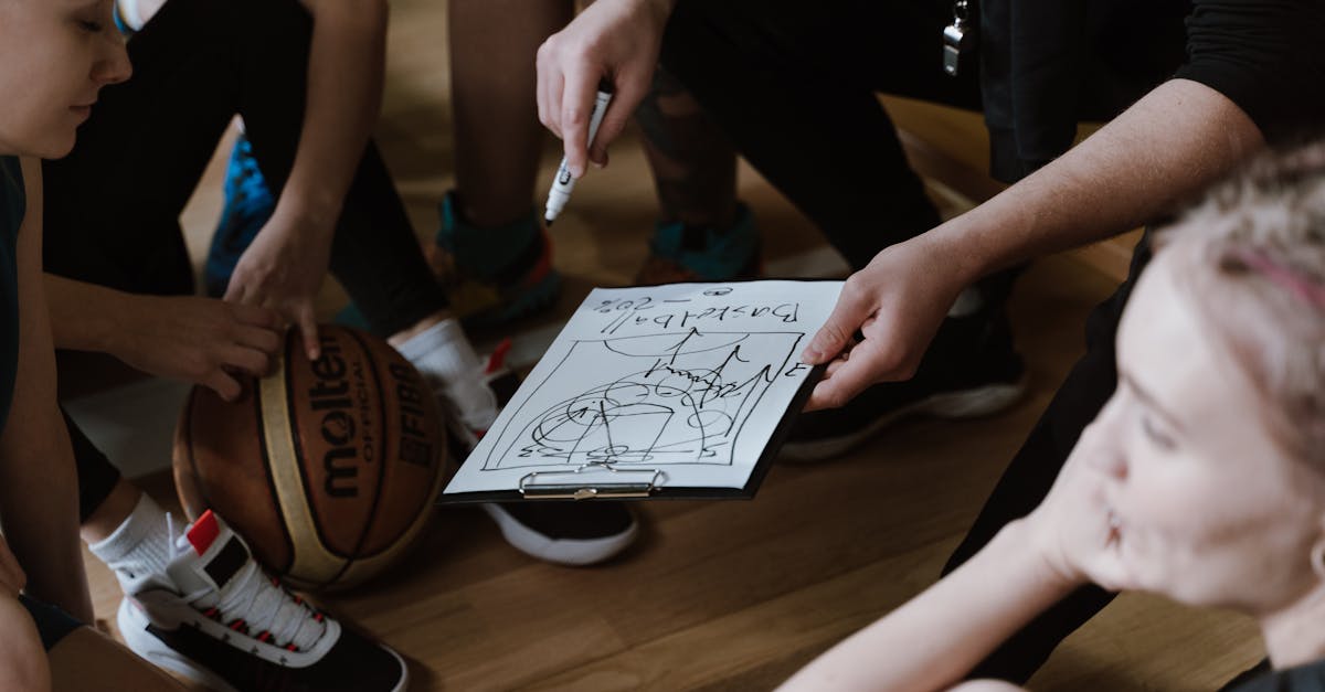 Close-up of a basketball team huddling with the coach discussing strategy indoors.