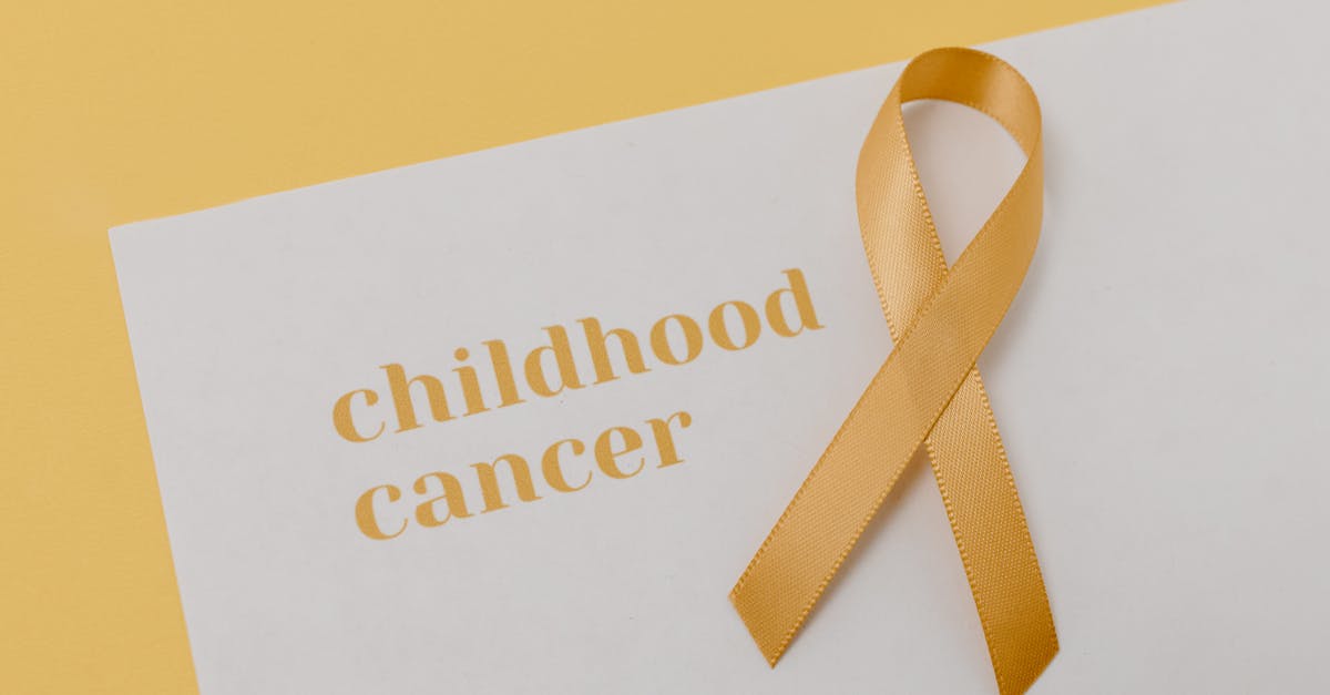 Gold ribbon symbolizing support for childhood cancer on a minimalist background