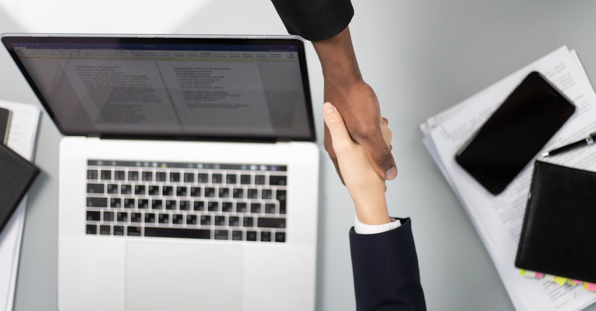 Overhead view of a professional handshake over a laptop, symbolizing business agreement.