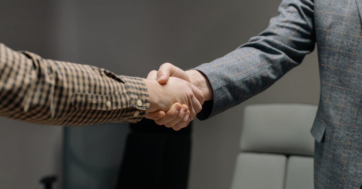 Close-up of two professionals shaking hands in an office, symbolizing successful business dealings.