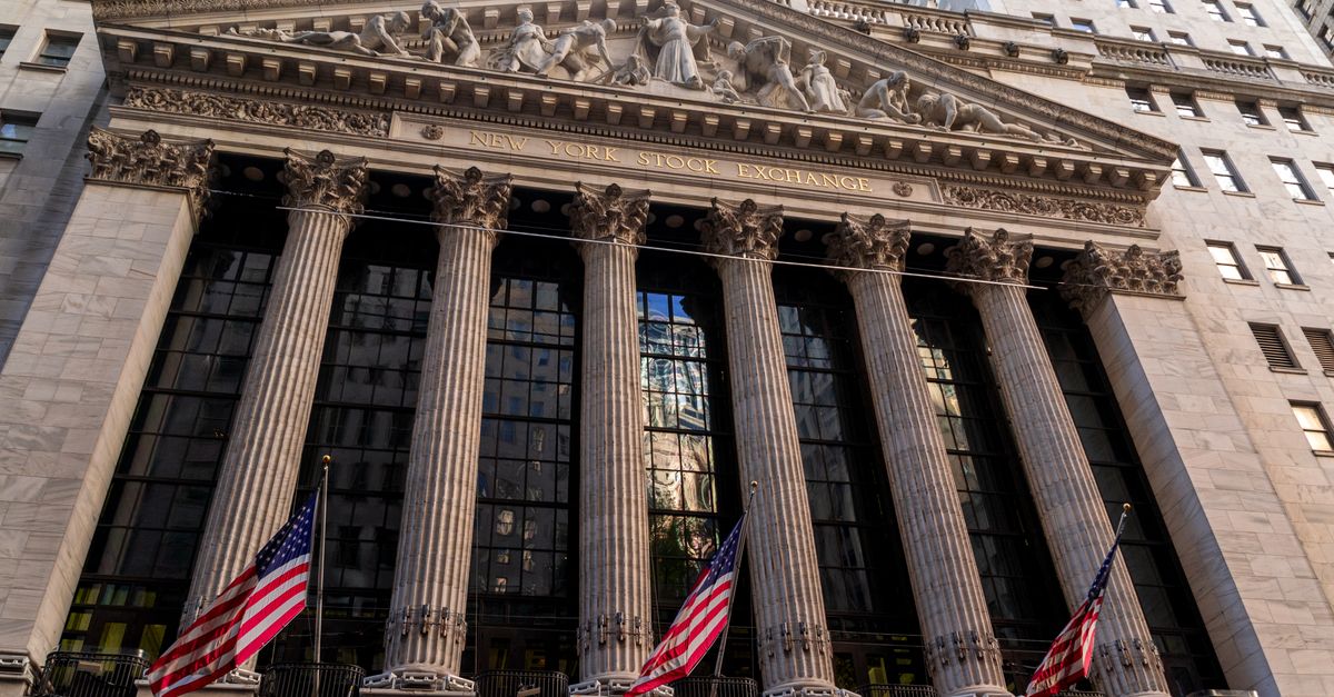 Iconic neoclassical facade of the New York Stock Exchange with American flags.