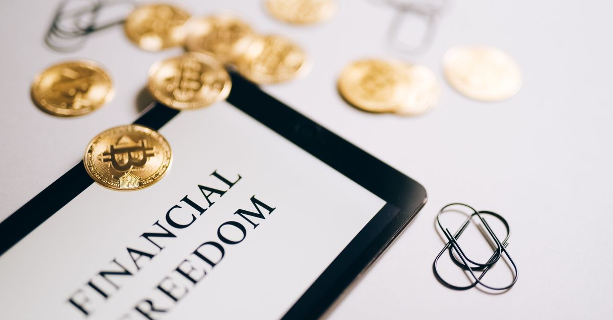 Close-up of Bitcoin coins and an iPad displaying 'Financial Freedom,' symbolizing modern digital savings.