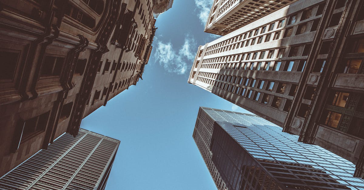 Upward perspective of New York skyscrapers against a clear blue sky, showcasing urban architecture.