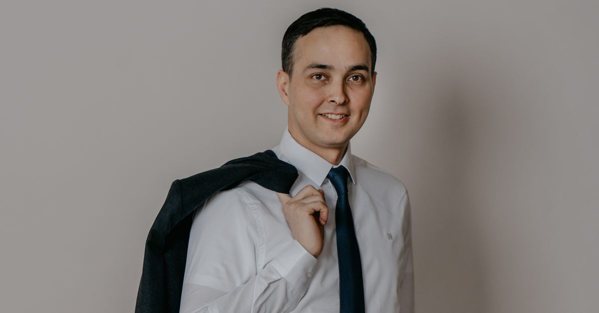 Portrait of a smiling businessman holding his jacket over his shoulder in a studio setting.
