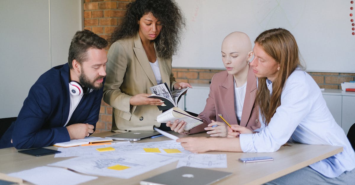 Group of multiracial businesspeople speaking and sharing data about project and analyzing reports in notebooks at table in office
