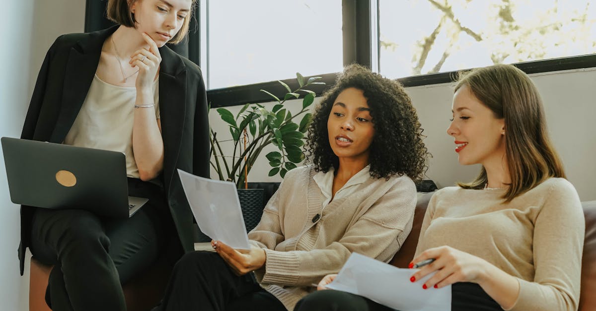 Three professional women engaged in a collaborative meeting in a modern office setting.