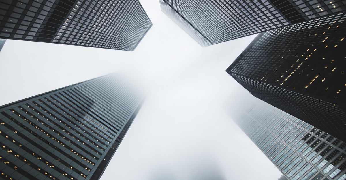 Misty city scene with towering skyscrapers disappearing into the fog, creating a moody urban environment.
