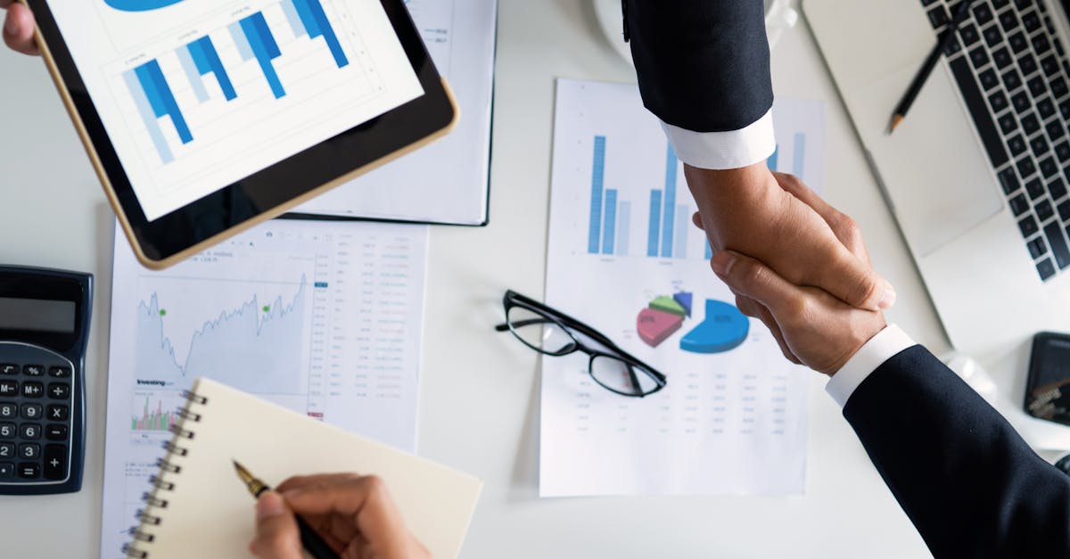 Business professionals handshake over graphs and charts in a corporate setting, symbolizing successful negotiation and agreement.