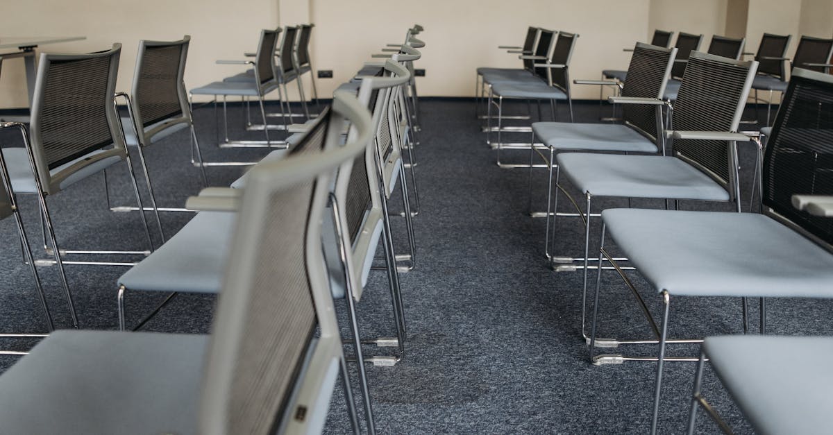 An empty meeting room with rows of modern chairs and carpet flooring, ready for use.
