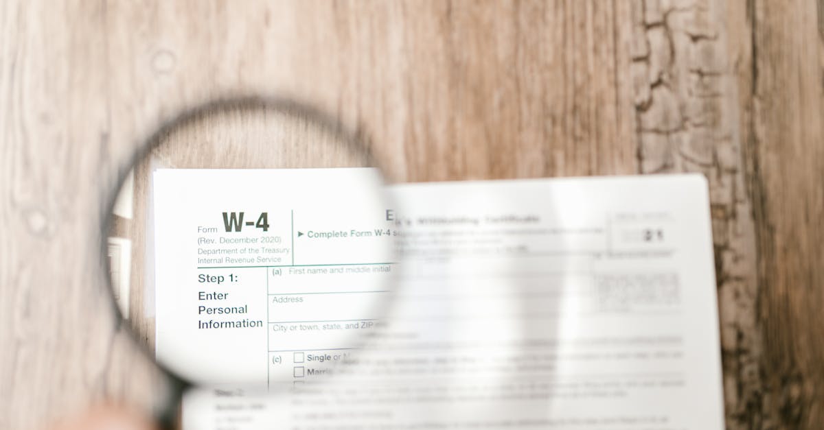 Close-up of a W-4 tax form through a magnifying glass on a wooden table.