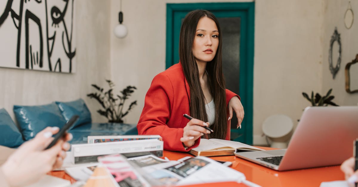 Professional woman in a red blazer working with colleagues in a modern office space.