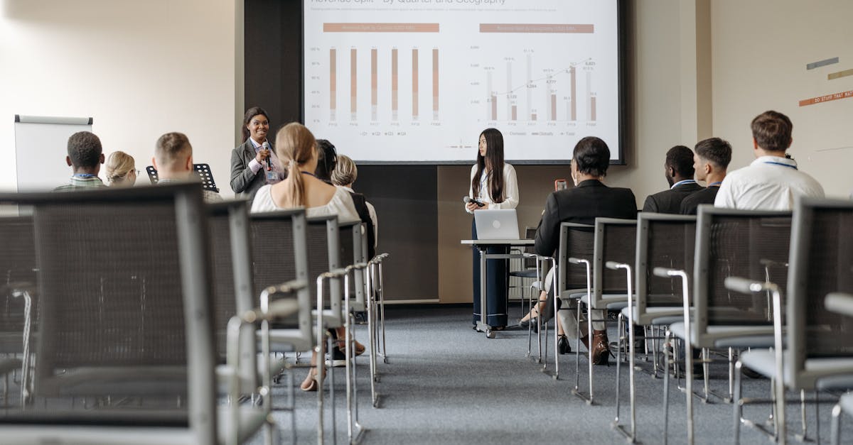 Business conference attendees listen to a presentation on revenue split by quarter and geography.