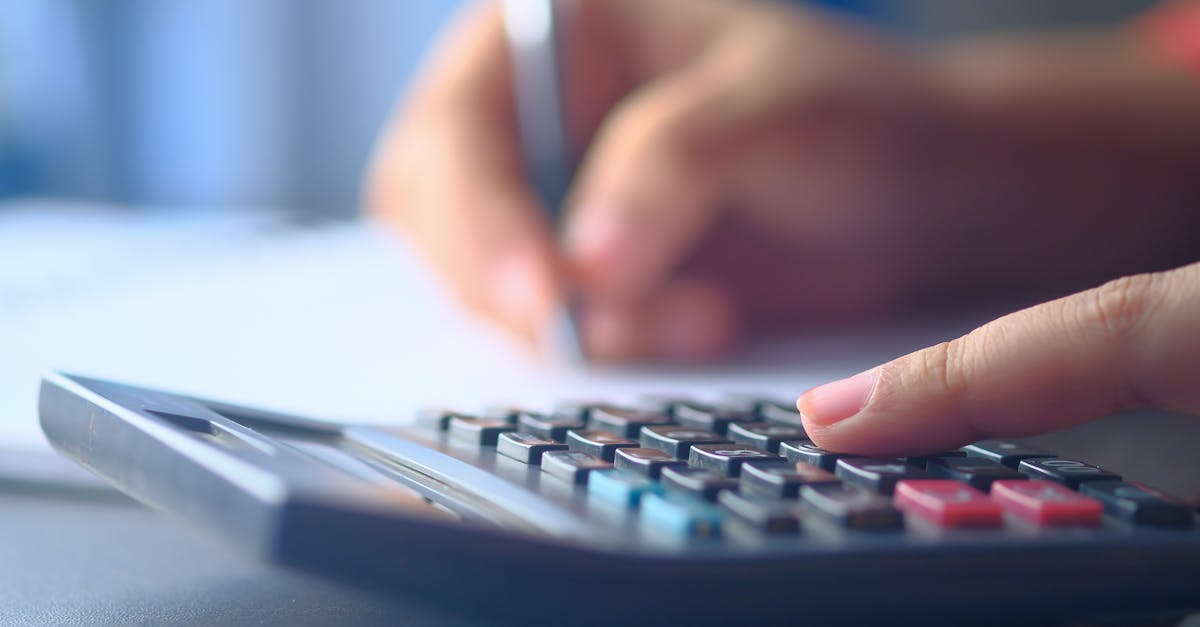 A close-up image of hands working on a calculator and writing, representing budgeting and financial planning.