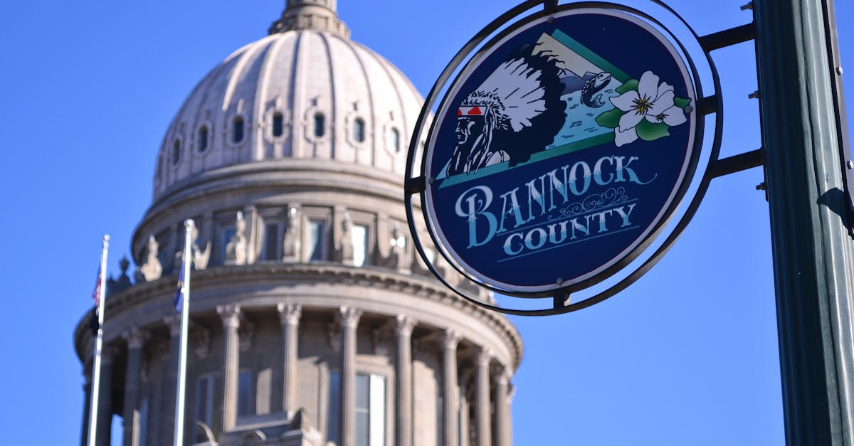 Idaho State Capitol Building dome with Bannock County sign under a clear blue sky in Boise.