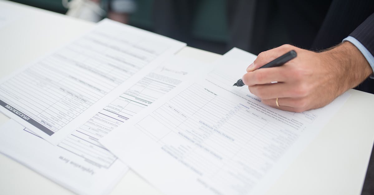 Close-up of a hand signing insurance documents in an office setting.